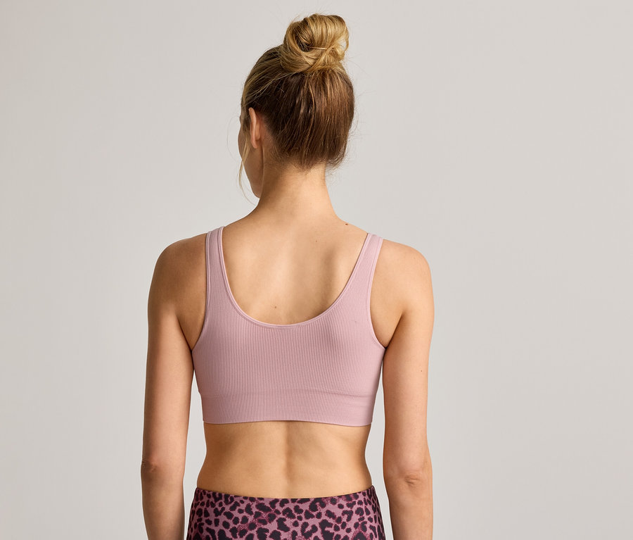 Hátulnézet egy kontyba fogott hajú nőről, aki bordázott sportmelltartót és leopárdmintás leggingset visel.