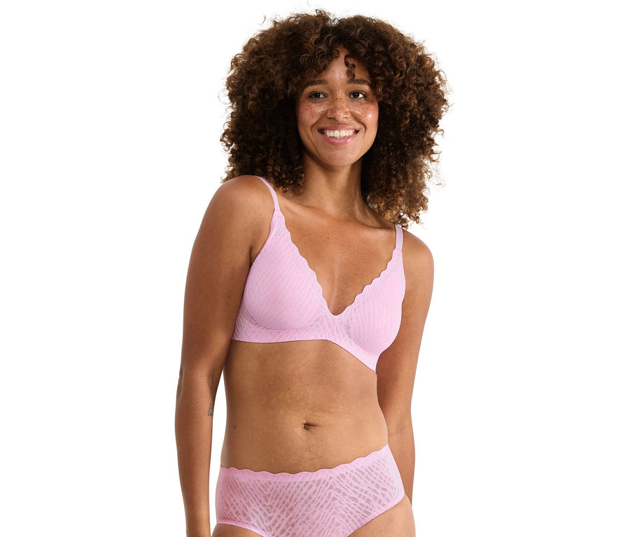 Göndör hajú nő világos rózsaszín melltartót és hozzáillő alsóneműt visel.