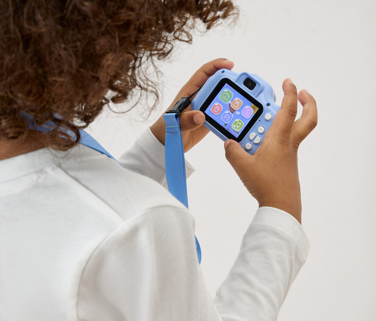 Egy gyermek egy világoskék játék fényképezőgépet tart maga előtt kék pánttal.