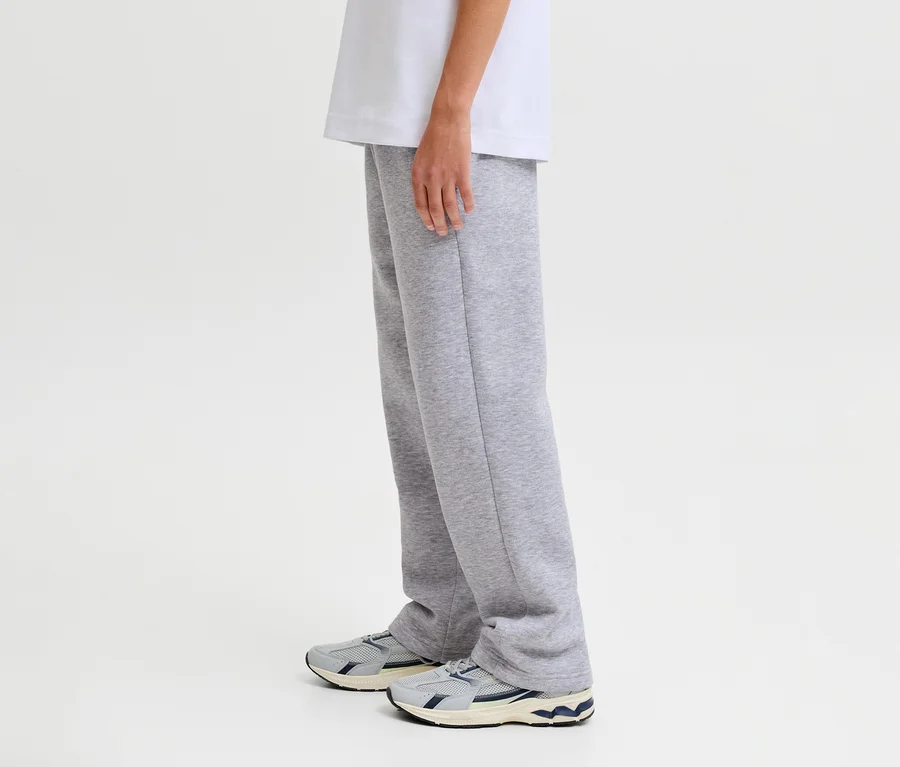 Egy személy szürke Jack&Jones Bradley szabadidőnadrágot és sportcipőt visel.