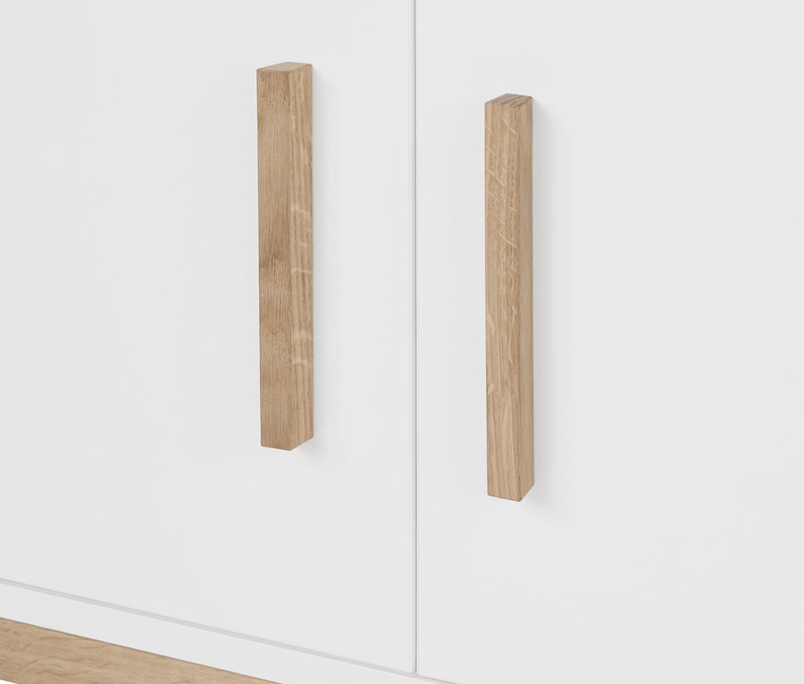 Egy fehér Eklund ruhásszekrény részlete fa fogantyúkkal.