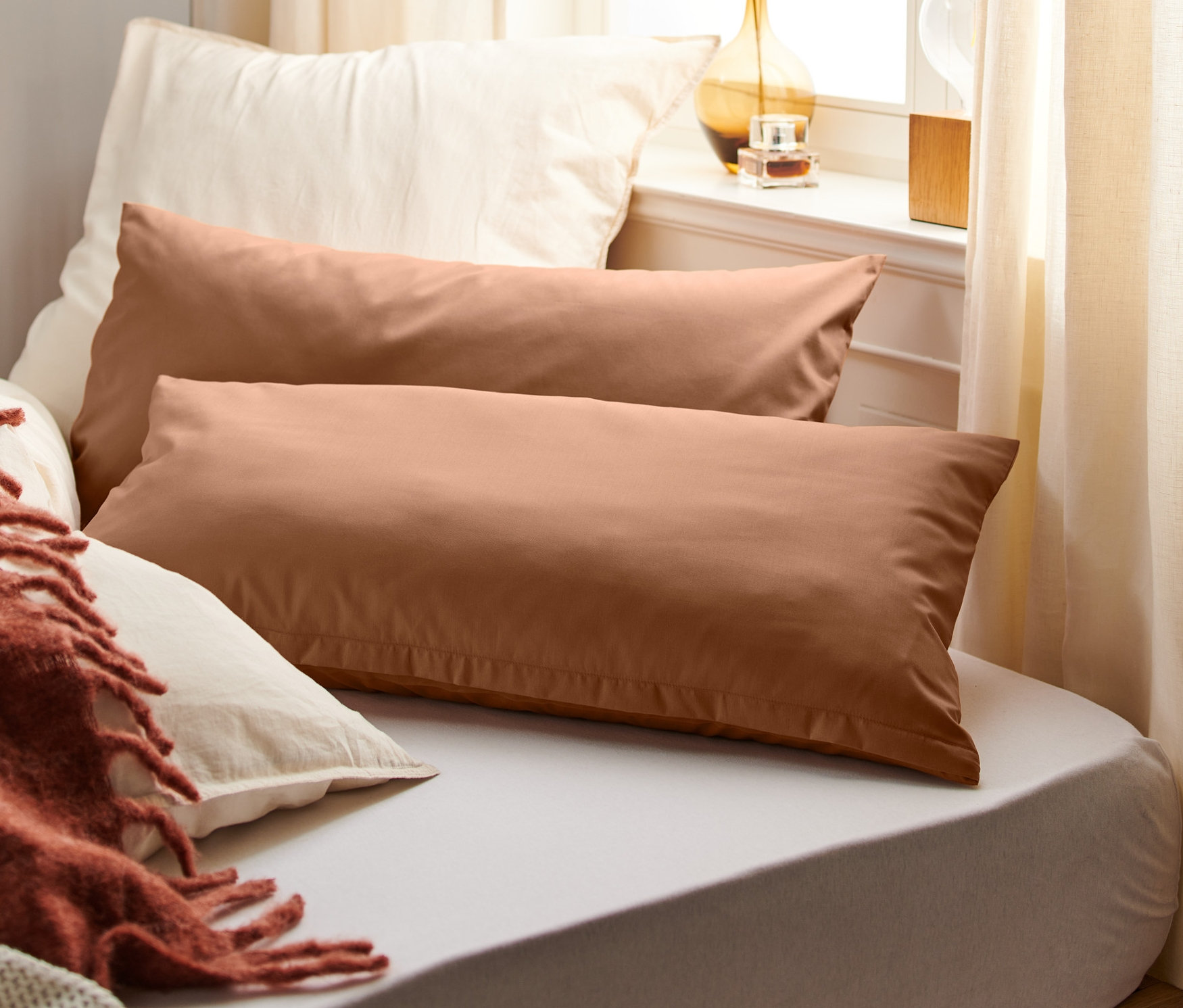 Két barna perkál párnahuzat fekszik egymás mellett egy ágyon.