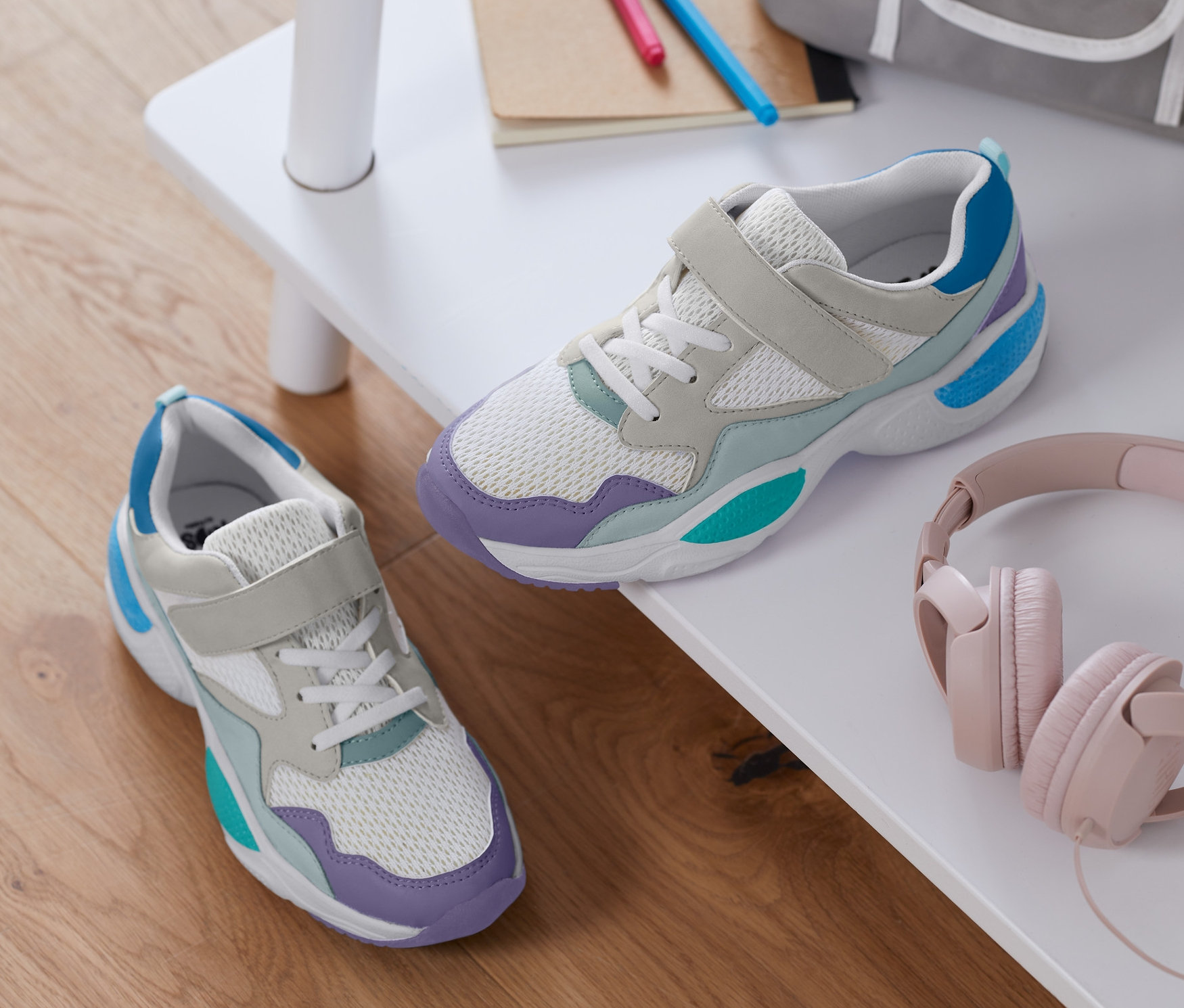 Lány sneaker cipő egy fehér polcon hátizsákkal és fejhallgatóval.