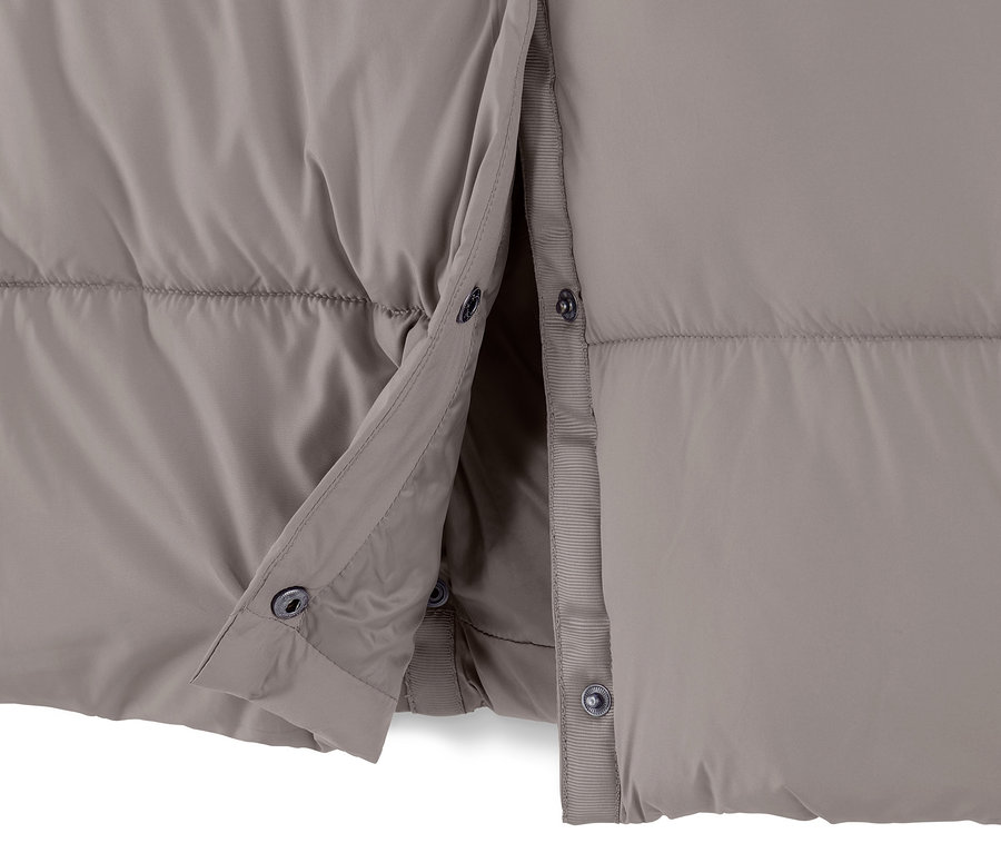 Egy taupe színű, steppelt kabát részlete, mely részben begombolva látható.