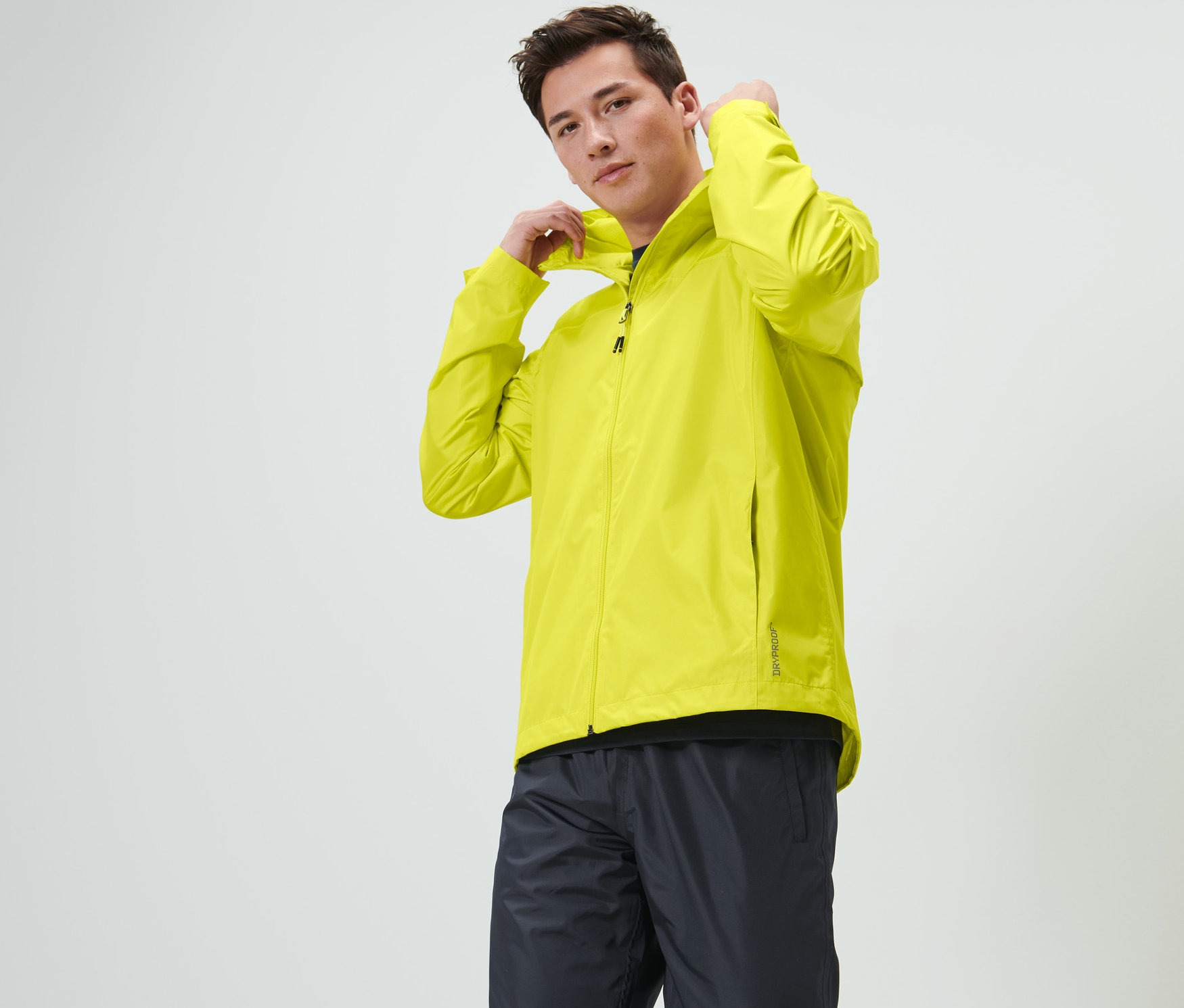 Férfi igazítja a kapucniját a lime színű unisex esőkabáton.