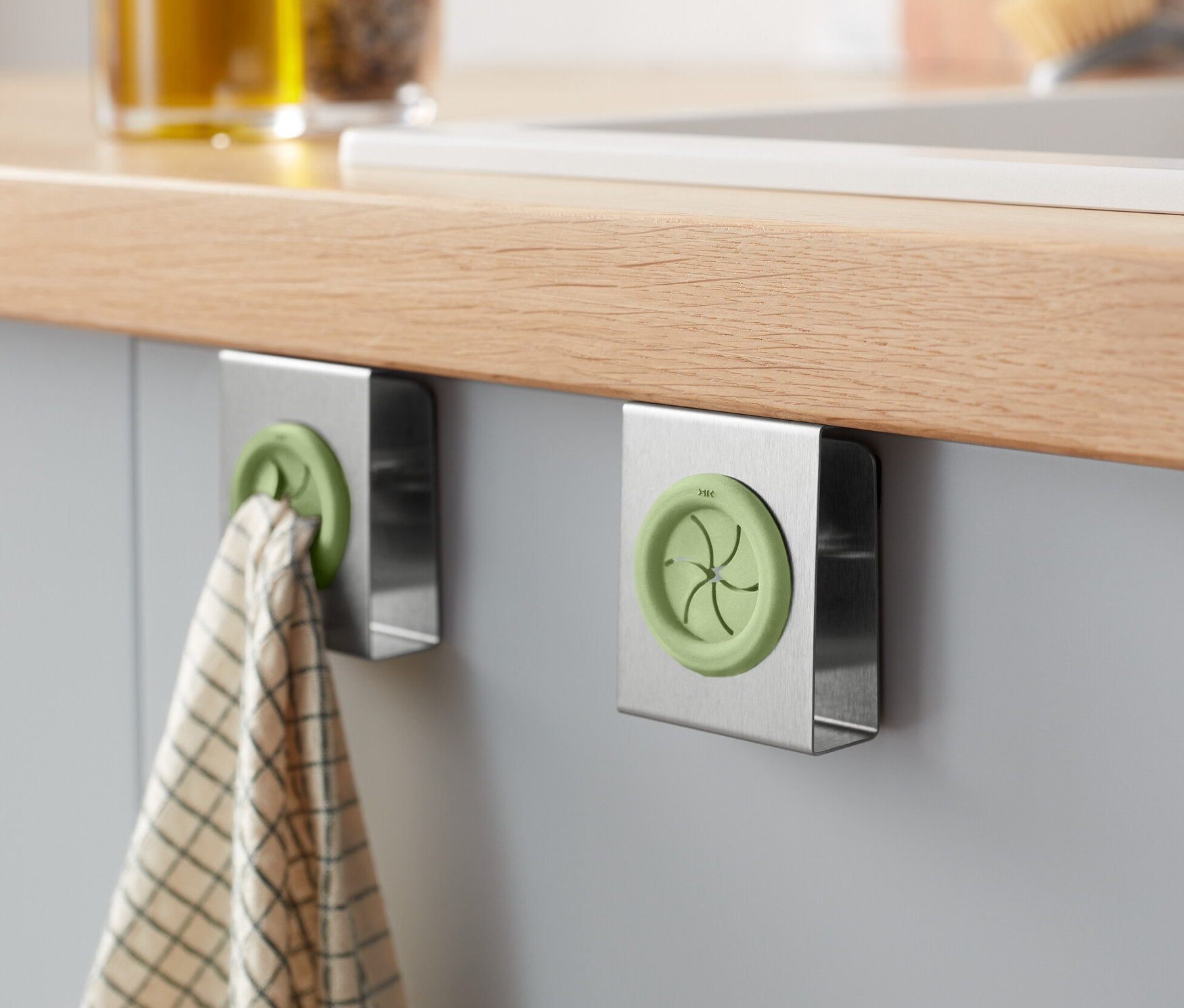 Két konyharuha-tartó van egy szekrényre rögzítve, az egyiken konyharuha lóg.