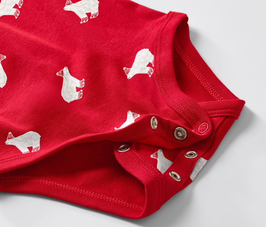 Egy piros, hosszú ujjú, jegesmedve mintás kisgyerek body részlete.