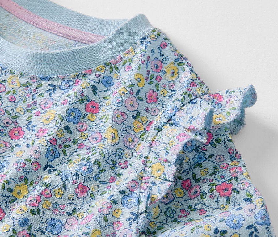 Virágmintás, hosszú ujjú kislány felső közelről.