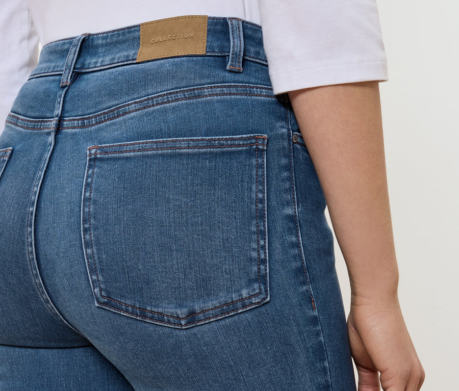 Kék farmernadrág hátuljának részlete, barna COLLECTION feliratú címkével.