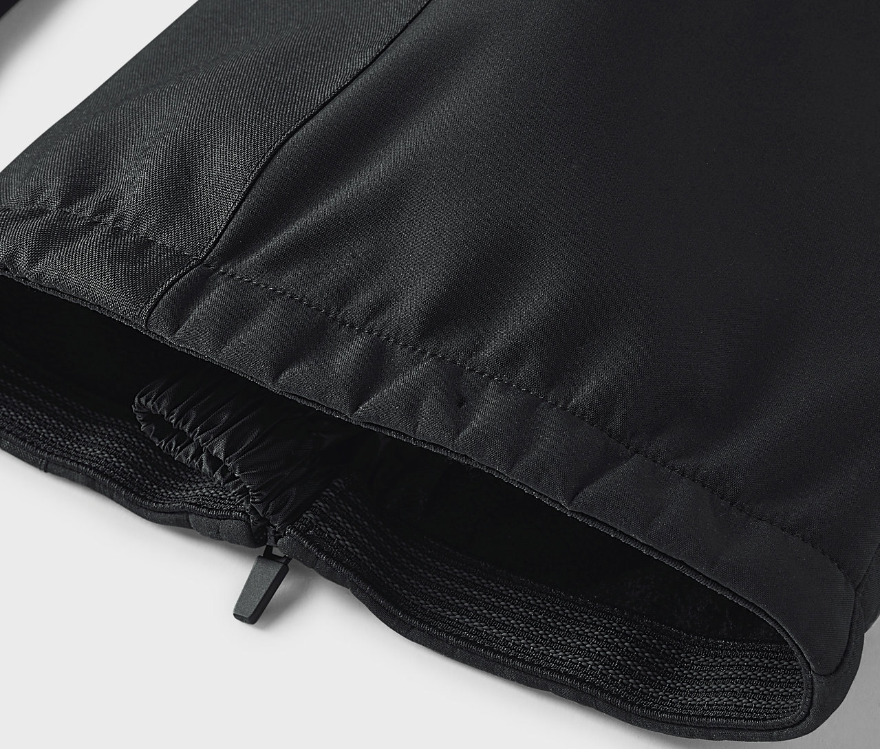 Egy fekete nadrág részlete cipzárral és gumírozott szegéllyel.