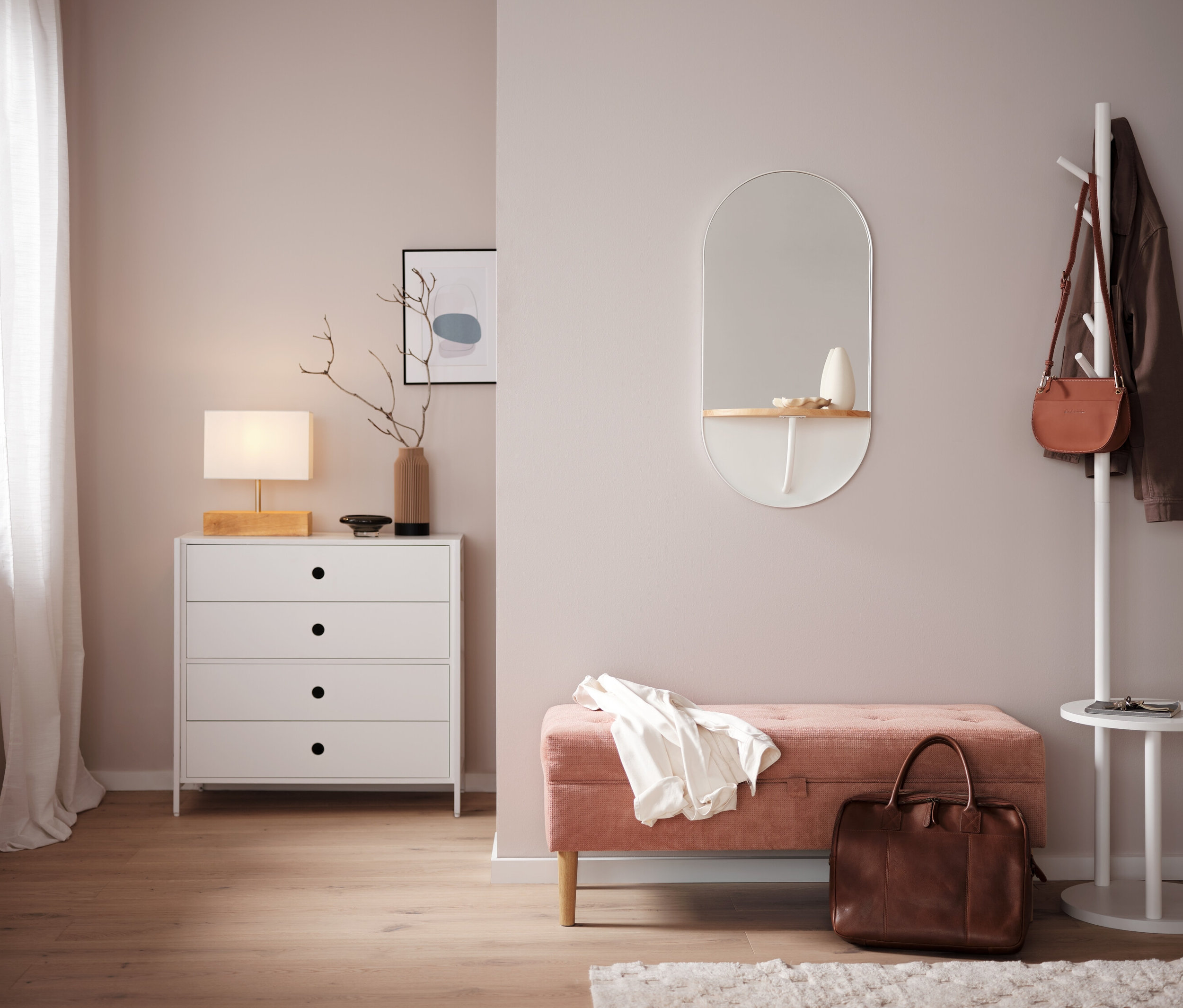 Hálószoba fehér komóddal, tükörrel és rózsaszín paddal.