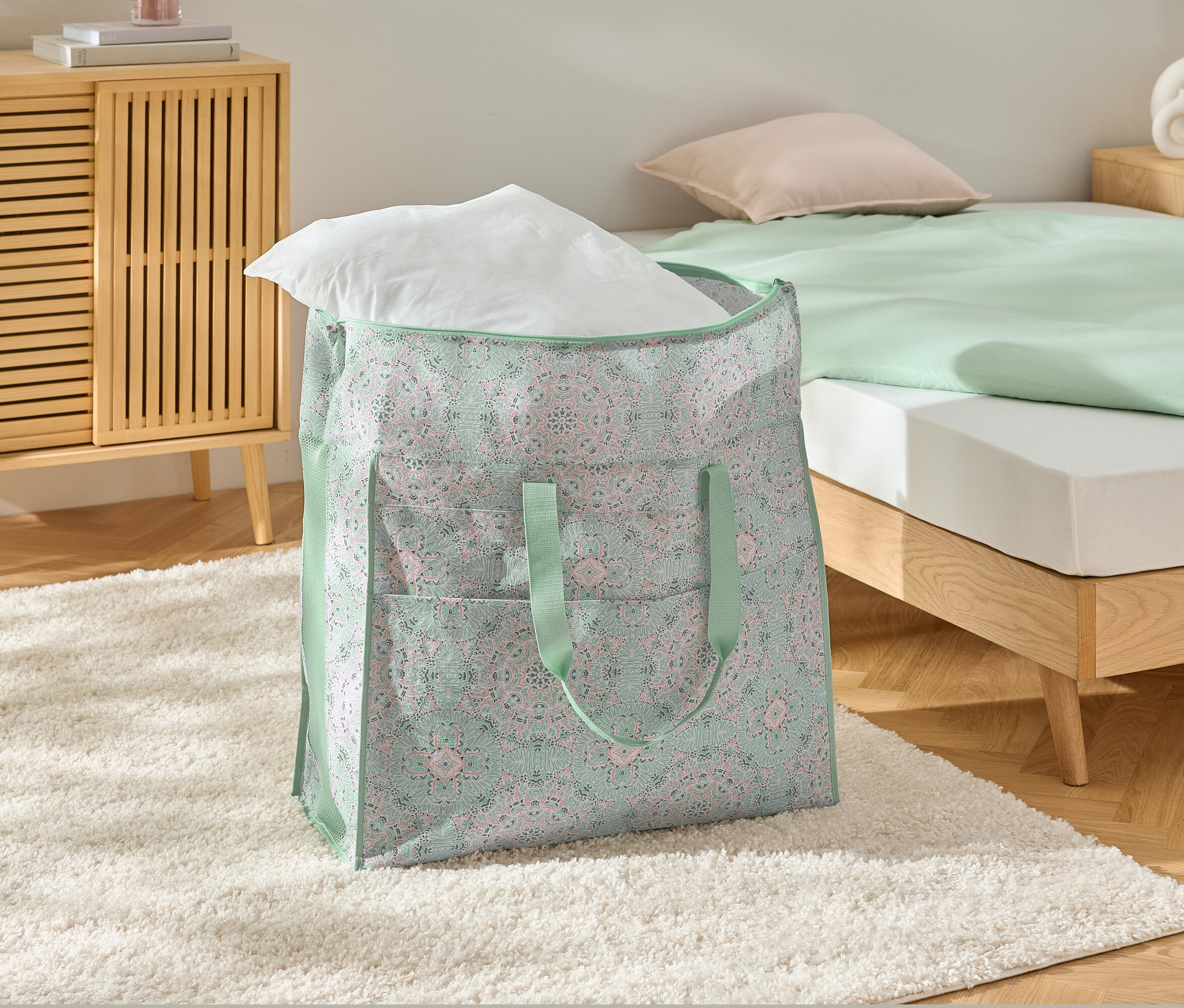 Egy jumbo ágyneműtartó táska fehér párnával egy fehér szőnyegen.