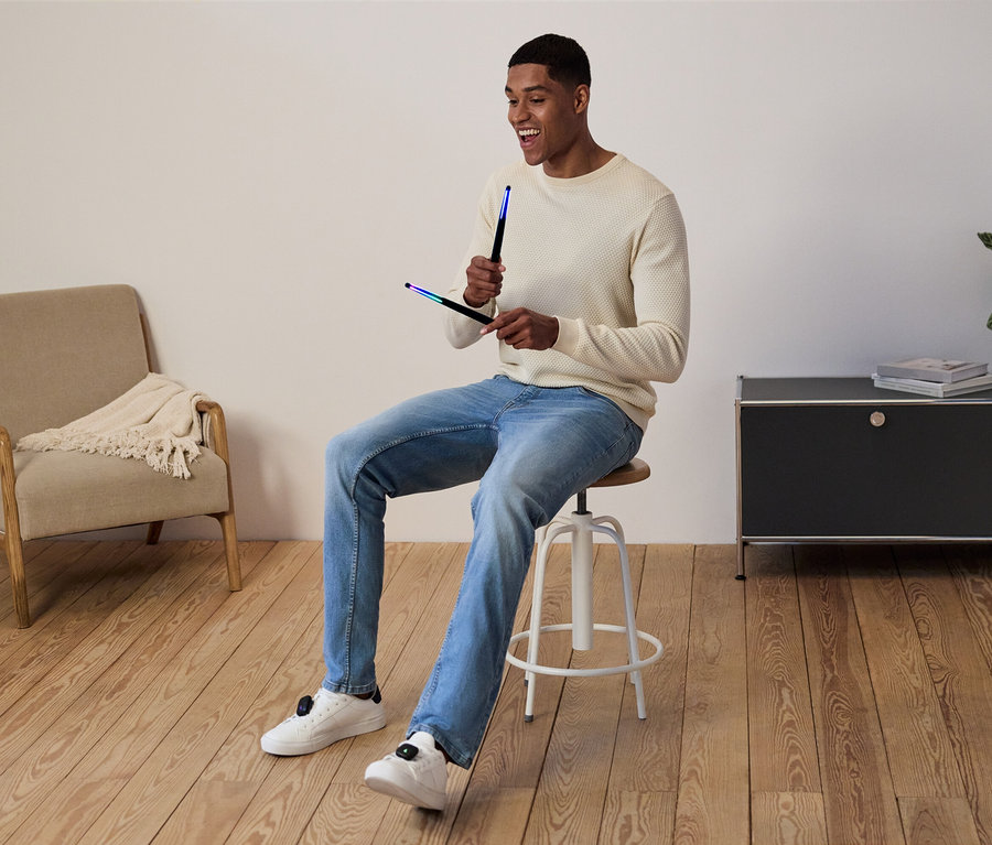 Férfi ül egy széken és világító rudakat tart a kezében.