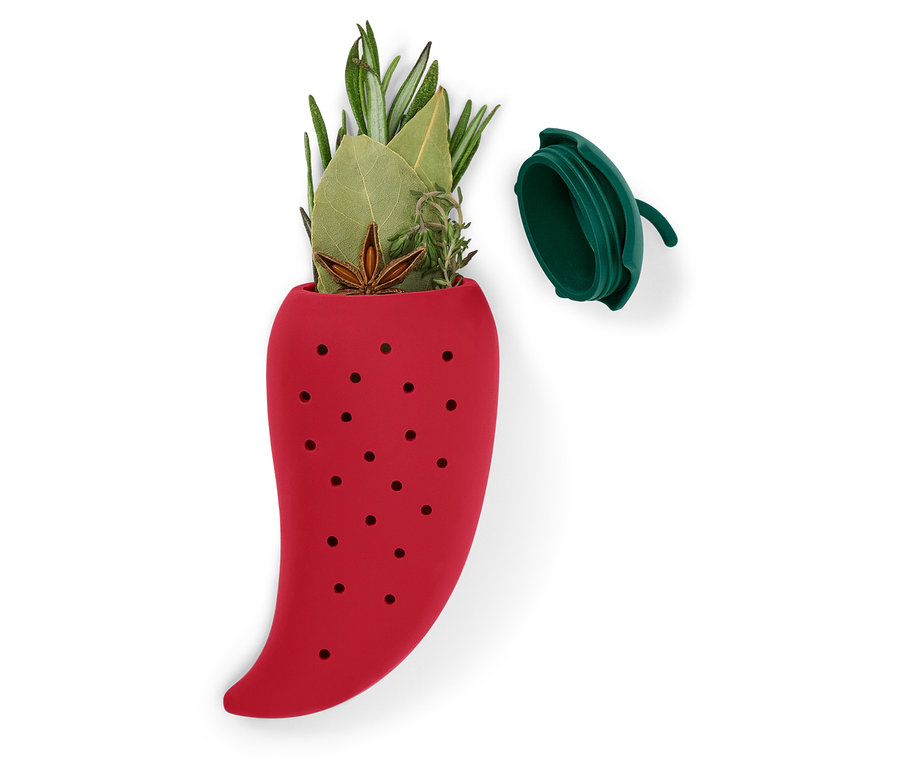 Piros, paprika formájú szilikon teatojás gyógynövényekkel töltve, a teteje mellette.