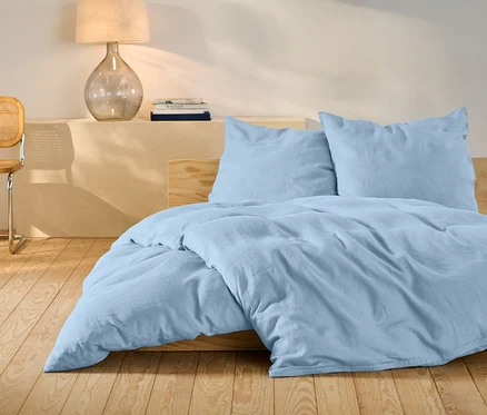 Világoskék, standard méretű ágyneműhuzat egy ágyon.