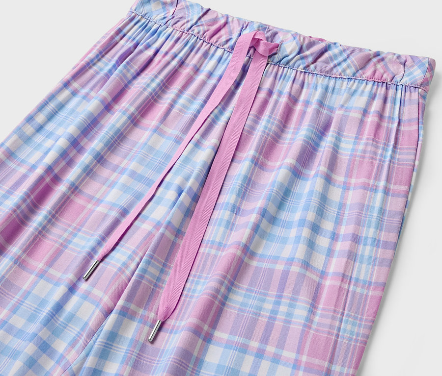 Női kockás nadrág részlete rózsaszín húzózsinórral.