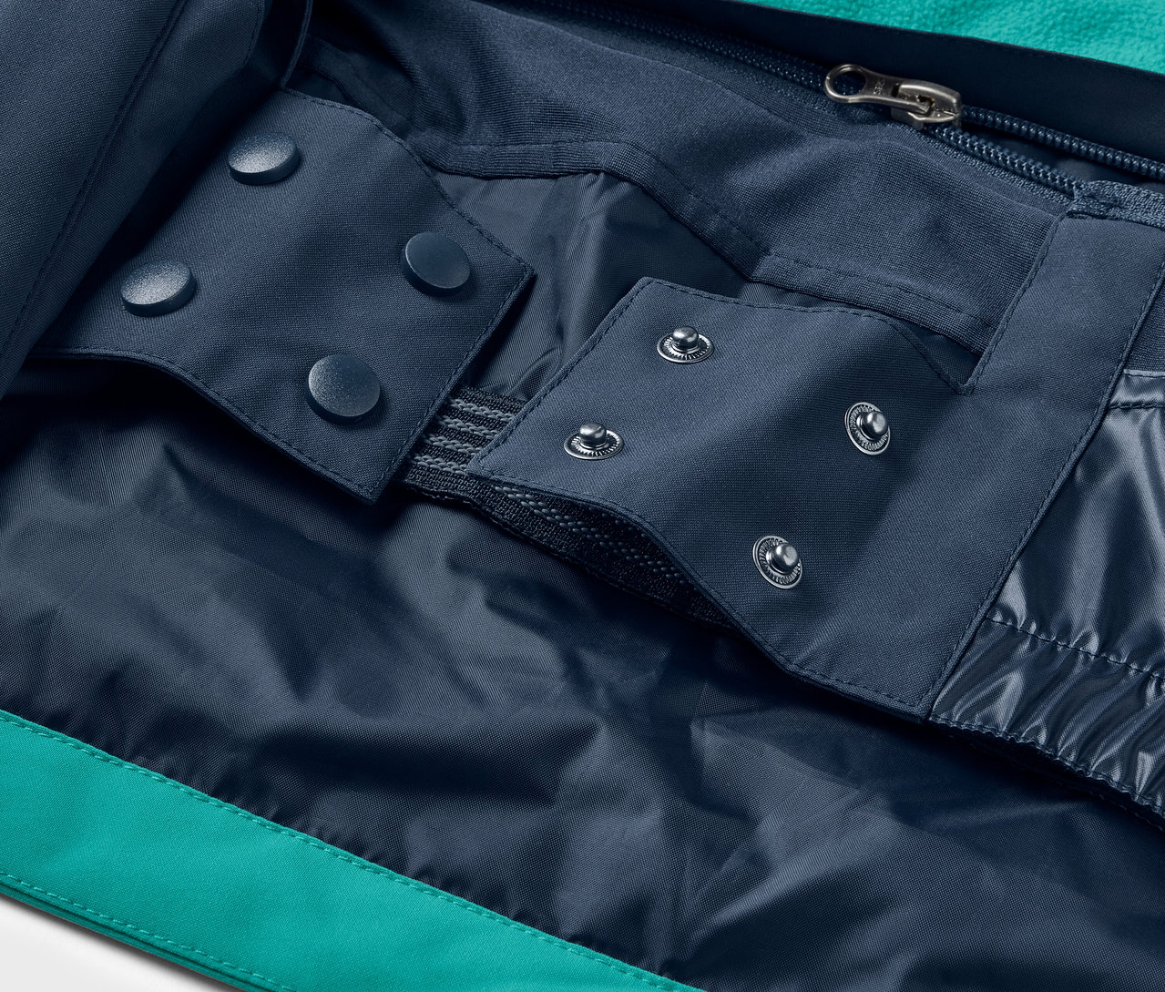 Kabát részlete kék patentokkal és cipzárral.