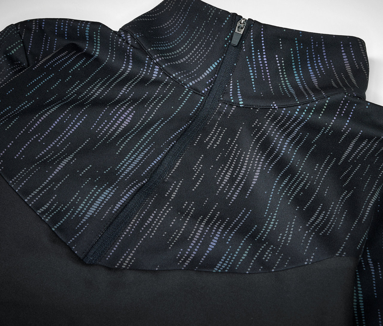 Egy fekete sportruházat részlete díszzárral és mintával.