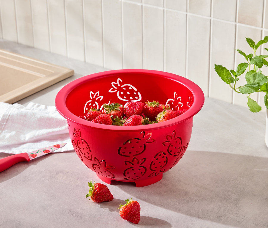 Egy eper mintás piros szűrőedény tele eperrel, mellette egy eper mintás kés.