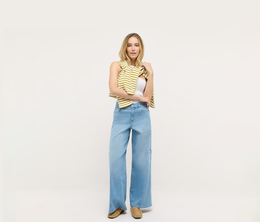 Egy nő áll fehér háttér előtt, és Angels denim »Liva« bőszárú cargo farmernadrágot visel.