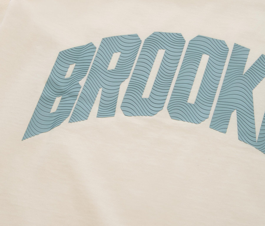 Krémszínű póló közeli képe kék "BROOKLYN" felirattal.