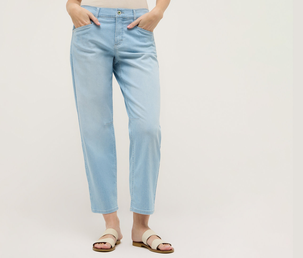 Nő világoskék Angels Denim »Evy Cool« O alakú nadrágban és szandálban. Kezei a zsebében.