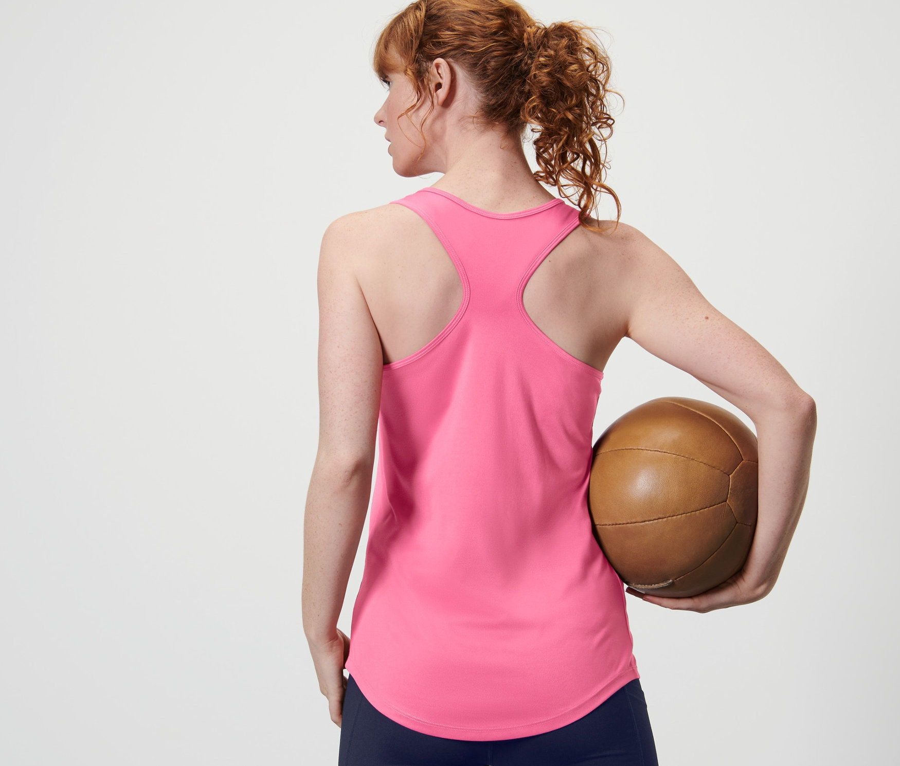 Hátulról látható nő egy barna labdát tart, és egy rózsaszín funkcionális topot visel egy 2 darabos szettből.