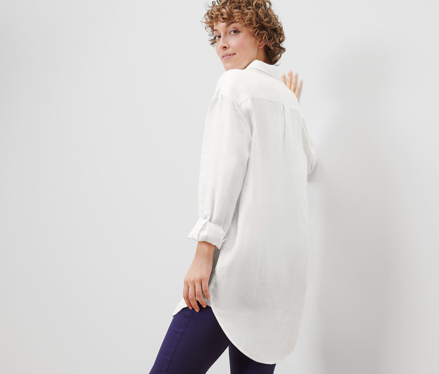 Nő néz a válla fölött, és lenvászon blúzban pózol.