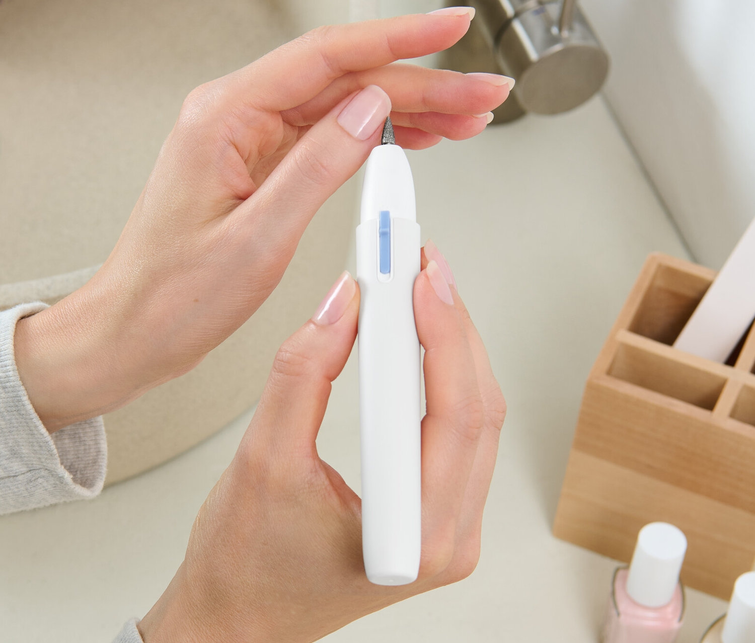 Nő manikűr-pedikűr készüléket tart a kezében.