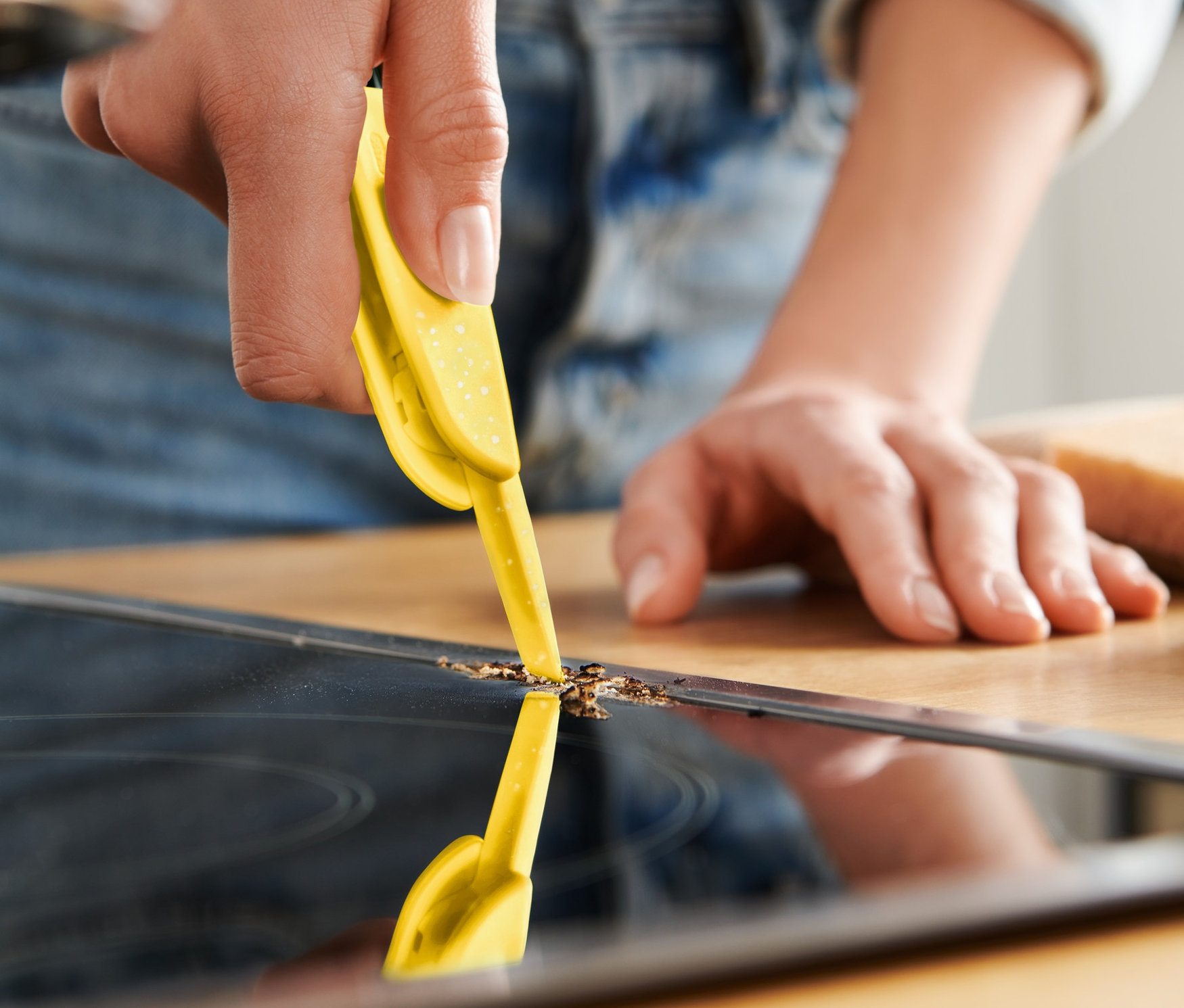 Nő tisztít egy főzőlapot egy 3 az 1-ben tisztítókefével.