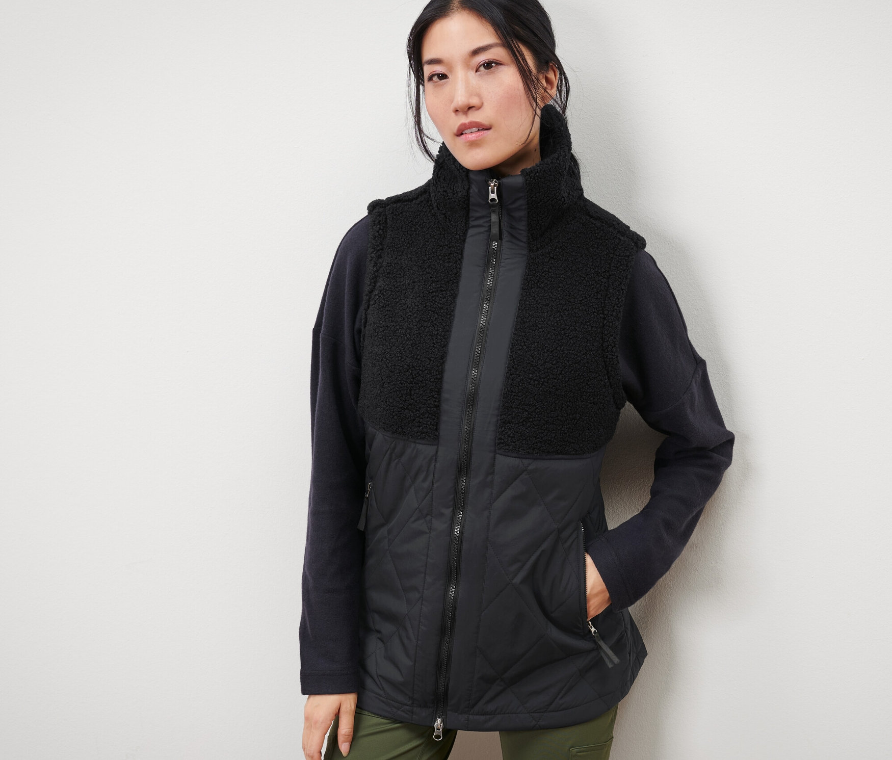 Nő visel fekete női hibrid plüssmellényt.