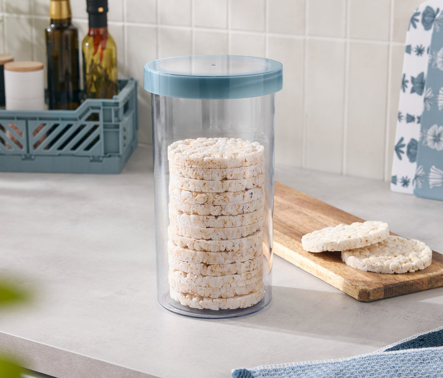 Rizskorongok vannak egymásra rakva egy kék fedelű tárolóedényben, kettő pedig egy fa deszkán fekszik.