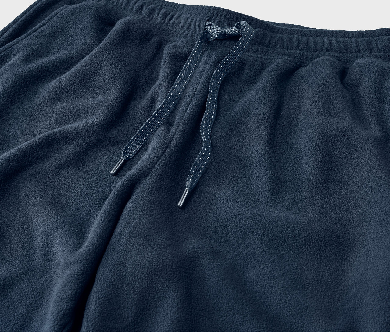 A sötétkék színű, húzózsinóros tréningnadrág részlete.