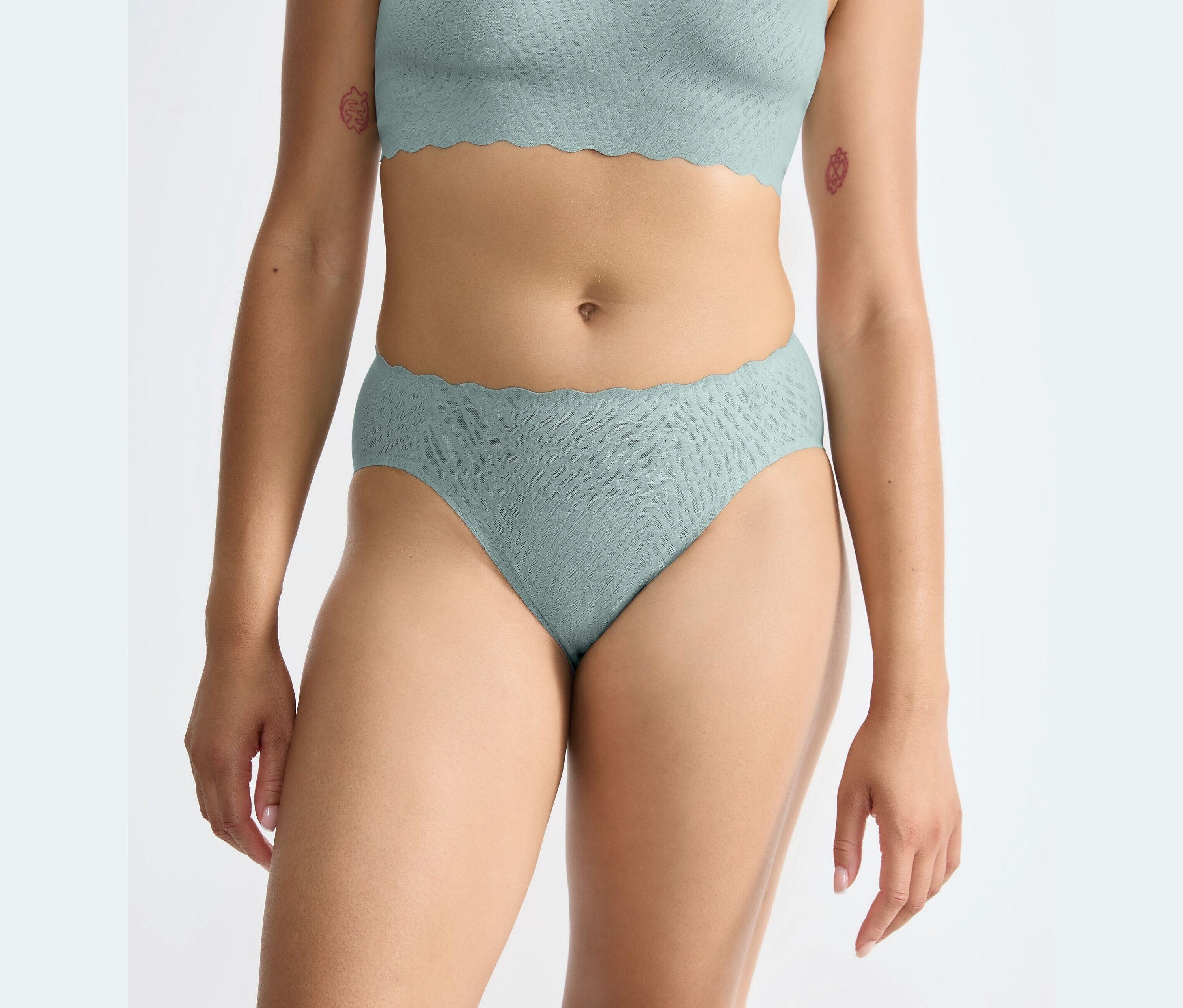 Egy nő sloggi ZERO Feel Bliss High leg alsót visel, elmosódó türkiz színben.