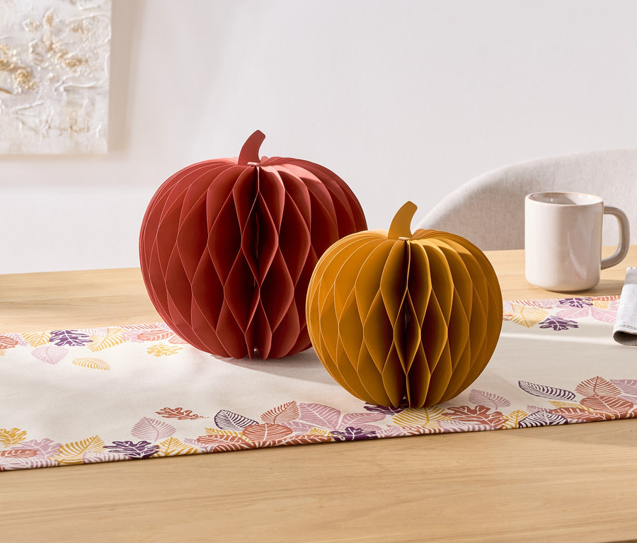 Az asztalon két dekoratív papírtök van, egy piros és egy sárga. Mellettük egy bögre és egy szalvéta található.