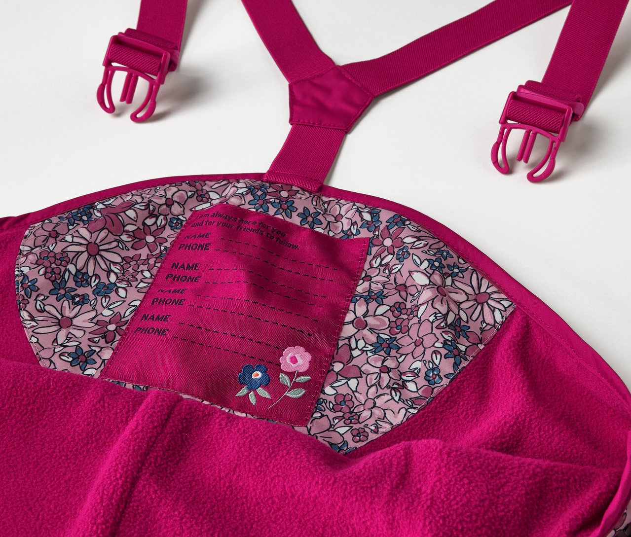 Részlet egy virágmintás gyerek termo esőnadrágról, beleértve olyan részleteket, mint a nadrágtartó és a névtábla.