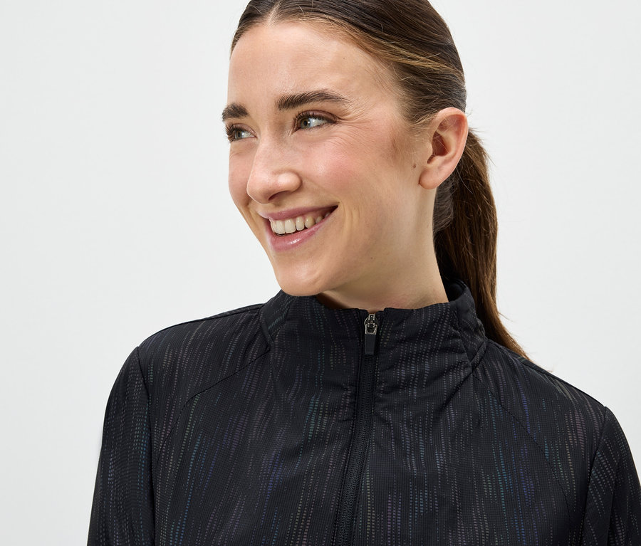 Portré egy mosolygó nőről fekete, cipzáras dzsekiben.