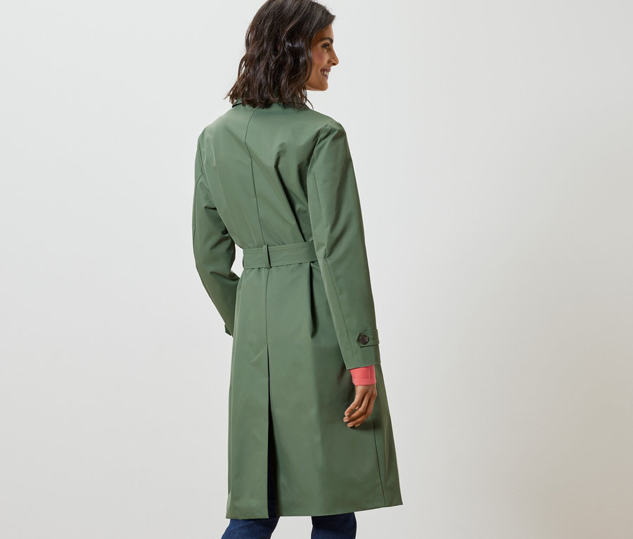 Egy nő a válla fölött néz hátra, és világoszöld ballonkabátot visel.