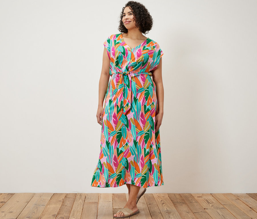 Egy nő áll és egy csomózott jersey ruhát visel.