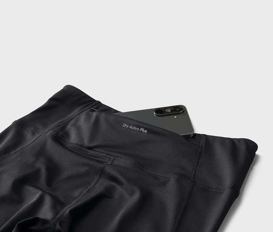 Fekete leggings "Dry Active Plus" felirattal és okostelefon a hátsó zsebben.