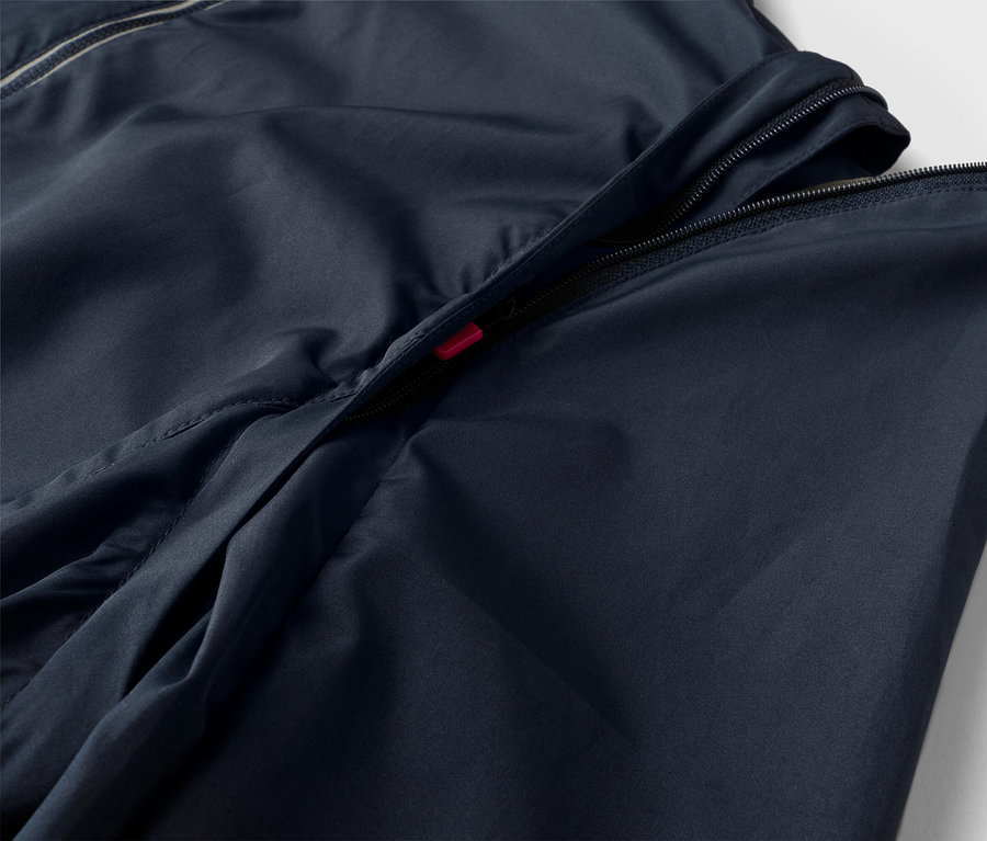 Egy sötétkék kabát közeli képe, részben nyitott cipzárral.