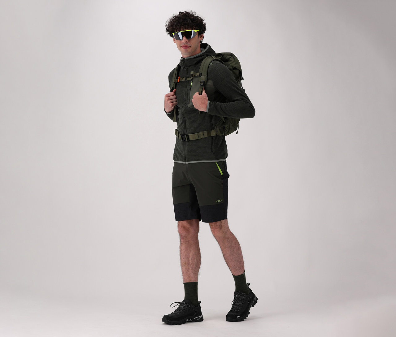 Férfi hátizsákkal és fekete CMP RIGEL LOW 2.0 WP férfi túracipővel világos háttér előtt pózol.