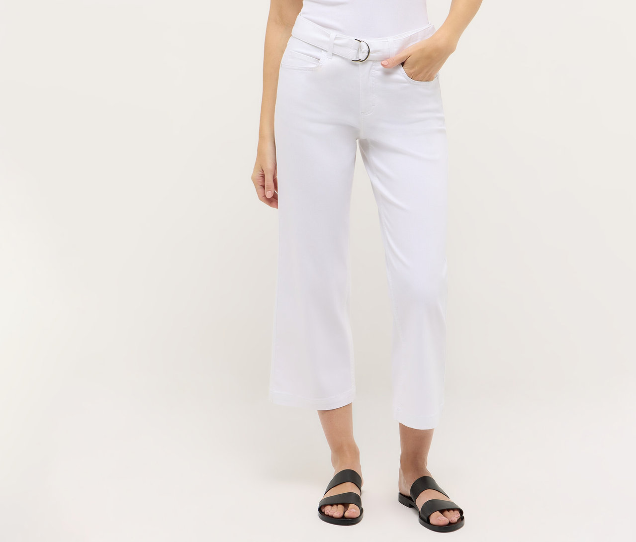 Egy személy fehér, cropped Angels denim »Linn City« farmert visz, ezüst övvel és fekete szandállal.
