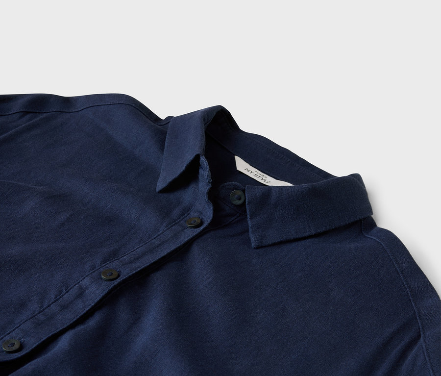 Egy sötétkék, galléros, gombos ing közeli képe.