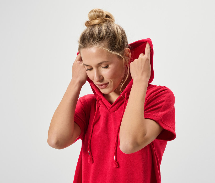 Kontyos nő visel egy piros kapucnis pulóvert.