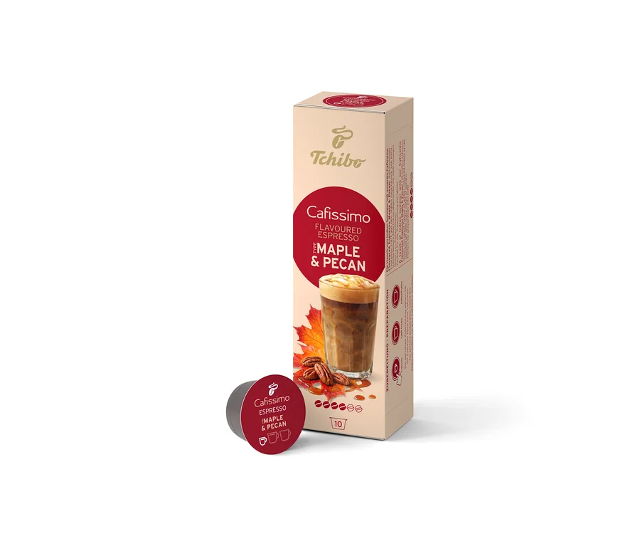 Egy bézs színű Cafissimo Flavoured Espresso Maple & Pecan (10 kapszula) doboz áll függőlegesen, előtte egyetlen sötétvörös kapszula fekszik. A dobozon kávéital, juharlevelek és pekándió látható.
