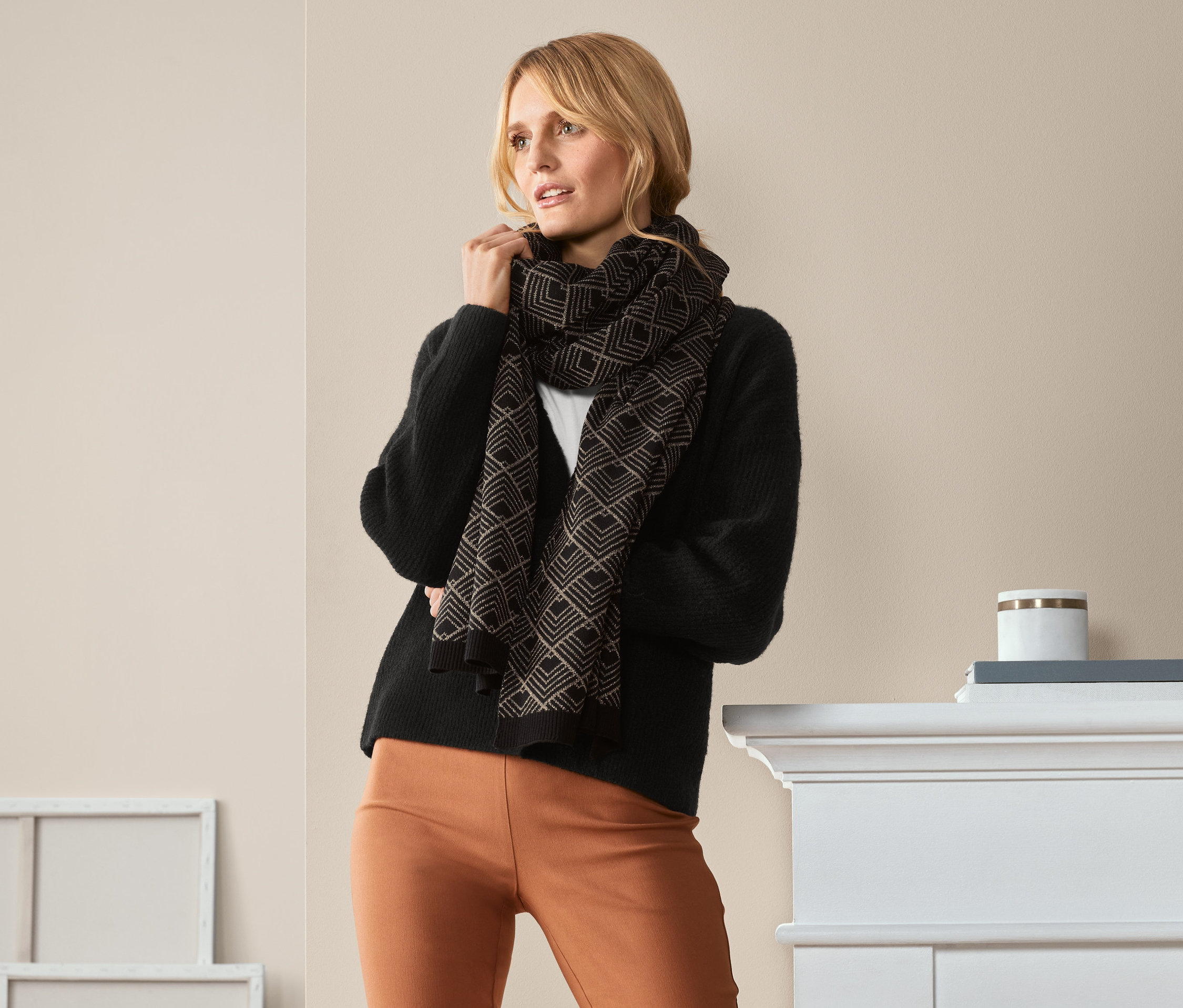 Nő pózol csillogó mintás kötött sálban.