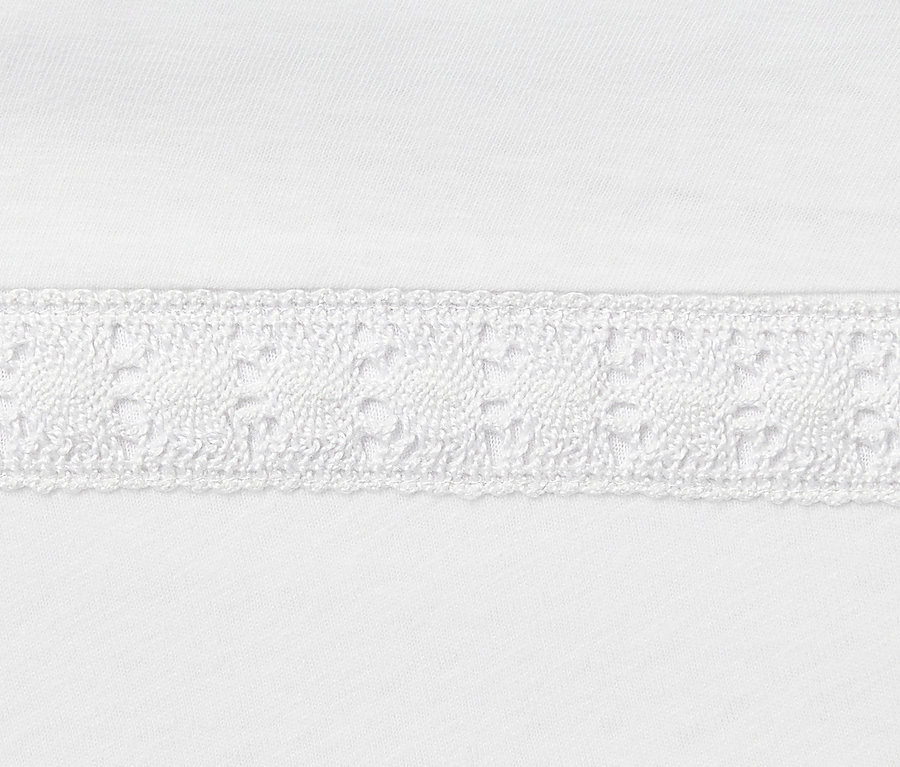Egy fehér, lenvászon keverékéből készült póló részlete horgolt szegéllyel.