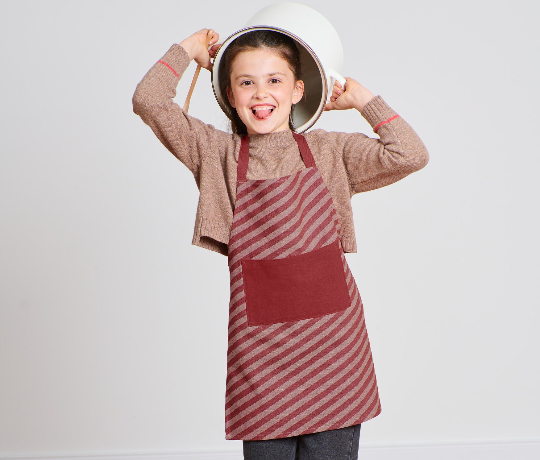 Lány konyhai köténnyel és egy fazékkal a fején.