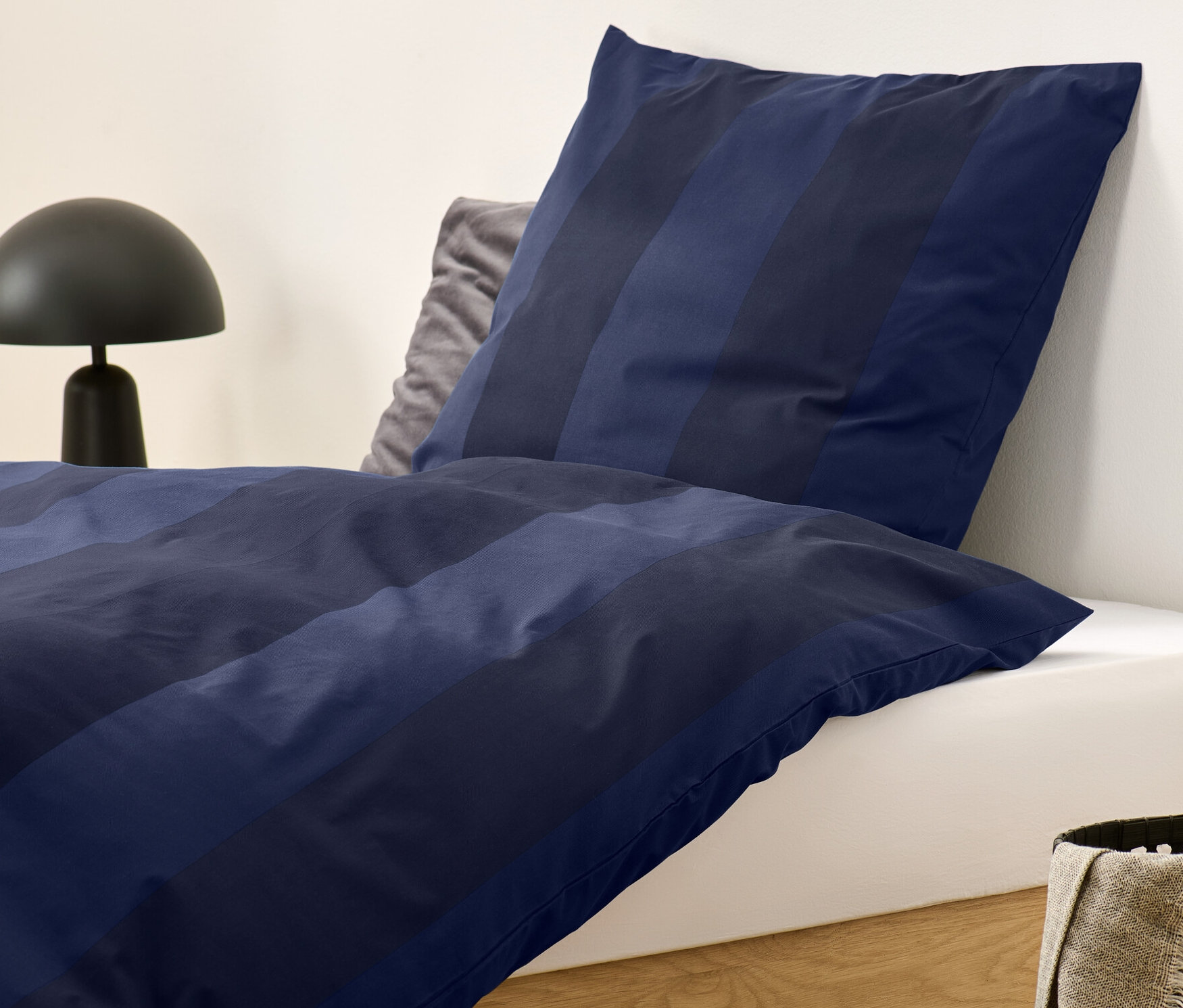 Kék csíkos, normál méretű flanel ágynemű egy ágyon.